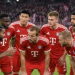 Een groep Bayern München-spelers in rode tenues verzamelt zich voor een wedstrijd in het stadion.