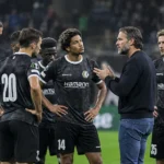 Een groep KAA Gent-spelers en een staflid overlegt op het veld na een wedstrijd.