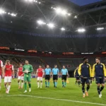 Spelers van Union en Hapoel Beer Sheva op het veld in een leeg stadion in Düsseldorf.