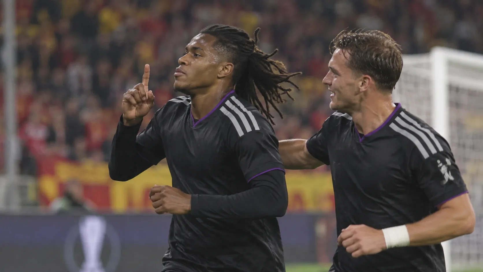 Twee Anderlecht-spelers in donkere wedstrijdkleding vieren samen een moment tijdens een Europese wedstrijd.