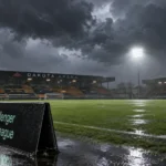 Leeg voetbalveld in een stadion met een fysieke Challenger Pro League-wedstrijdaanduiding tijdens stormweer.