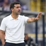 Mo Messoudi geeft instructies langs de zijlijn in een wit poloshirt.