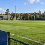 Leeg trainingsveld van de jeugdacademie met een vast KRC Genk-clubembleem aan de rand.