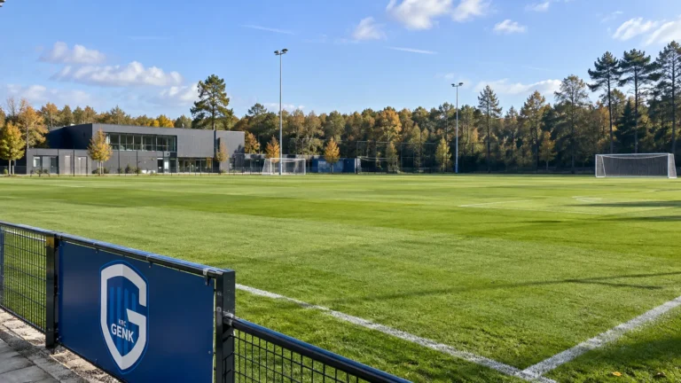 Leeg trainingsveld van de jeugdacademie met een vast KRC Genk-clubembleem aan de rand.