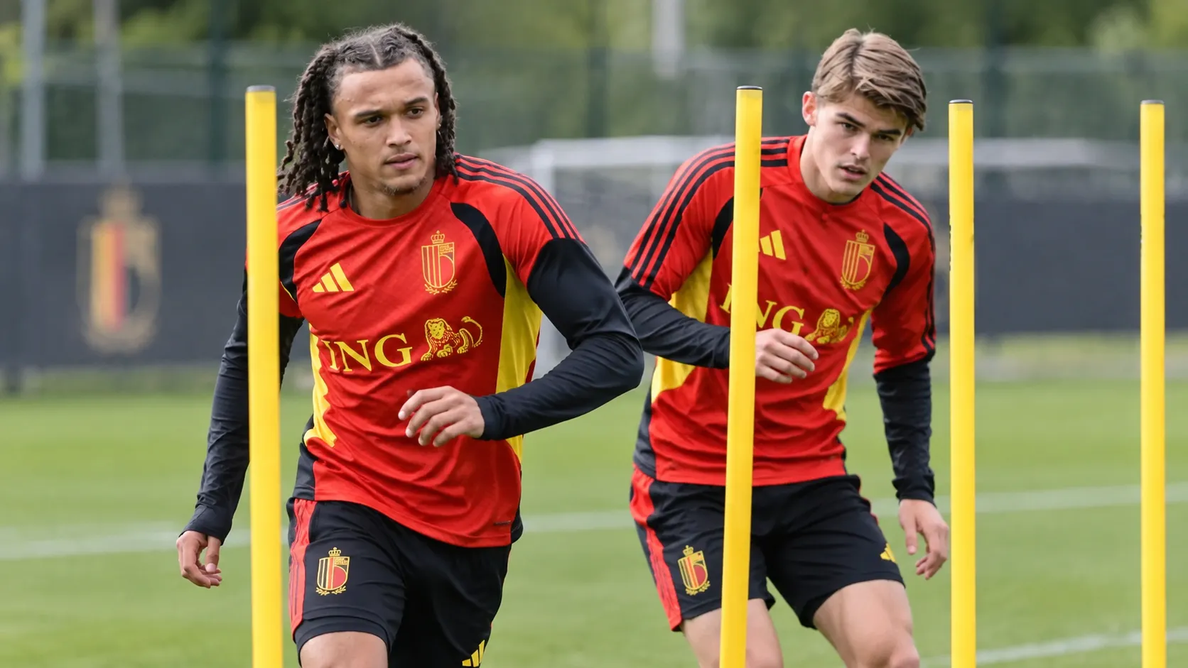 Twee spelers van de Rode Duivels trainen tussen gele slalompalen.