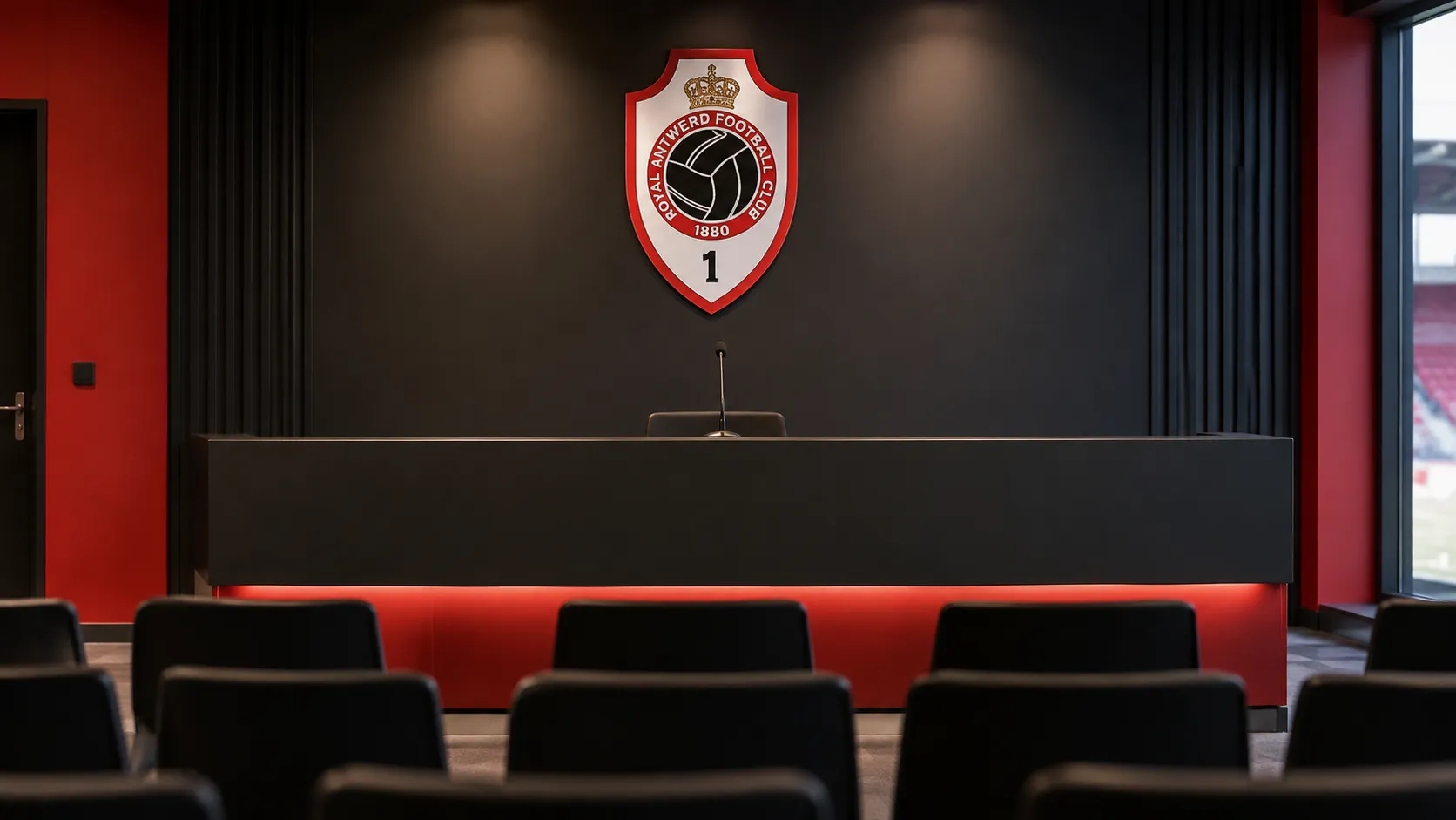 Een leeg persconferentiepodium van Royal Antwerp FC met een clubembleem op de achterwand.