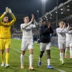Een groep KRC Genk-spelers en stafleden bedankt na een avondwedstrijd de supporters.