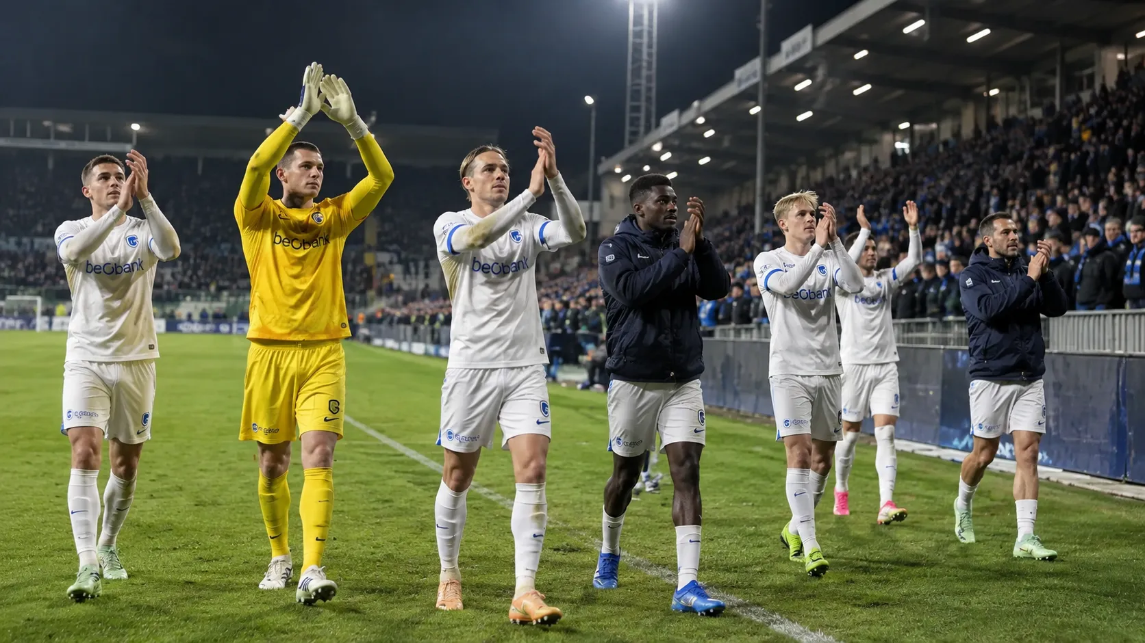 Een groep KRC Genk-spelers en stafleden bedankt na een avondwedstrijd de supporters.