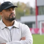 Vincent Kompany in een zwarte pet en lichte jas op het trainingscomplex van Bayern München.
