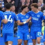 Een groep spelers van Brighton moedigt elkaar aan langs het veld tijdens een wedstrijd.