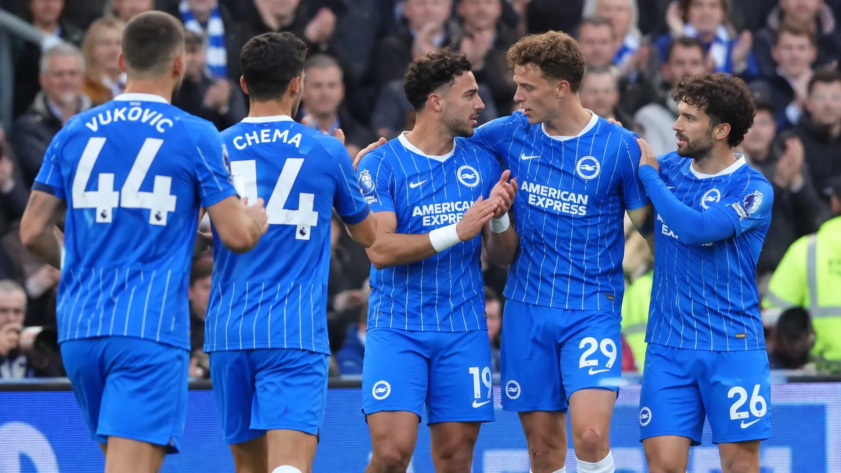 Een groep spelers van Brighton moedigt elkaar aan langs het veld tijdens een wedstrijd.