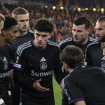 Een groep Anderlecht-spelers in zwarte wedstrijdshirts op het veld na afloop van een match.