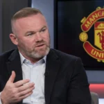 Wayne Rooney spreekt in een studiogesprek, met een Manchester United-embleem op een scherm achter hem.