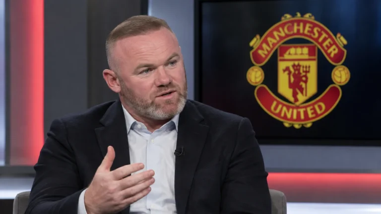 Wayne Rooney spreekt in een studiogesprek, met een Manchester United-embleem op een scherm achter hem.