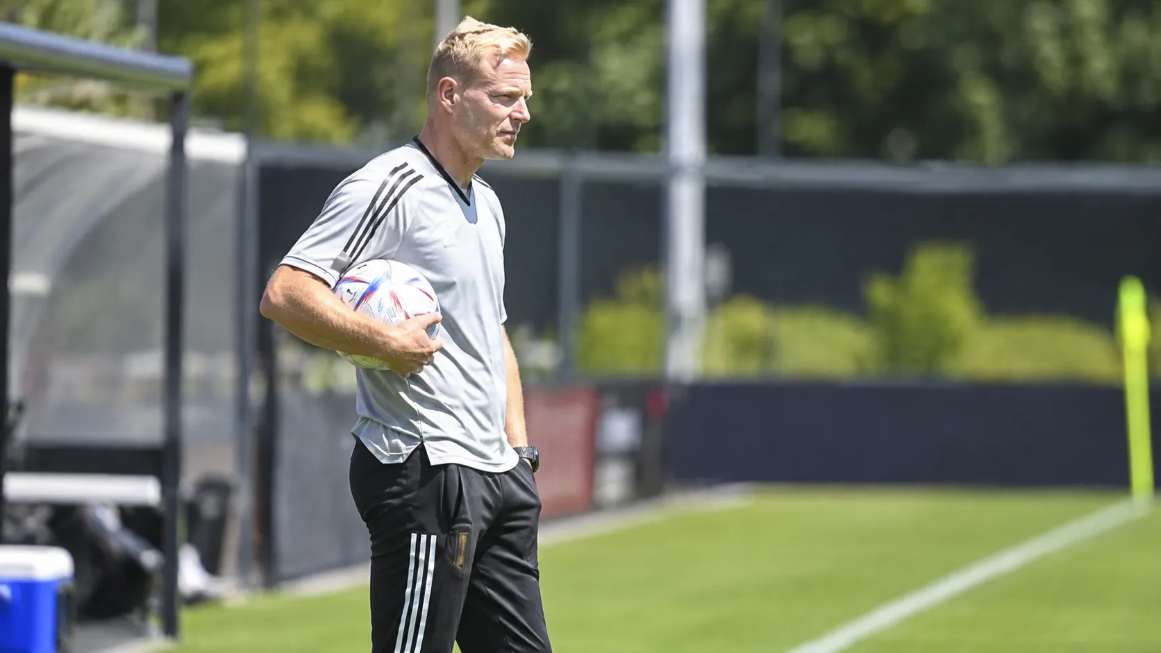 Olivier Deschacht in grijze trainingskleding aan de rand van een voetbalveld.