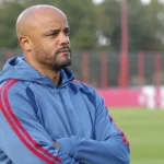 Vincent Kompany observeert een training naast een oefenveld.