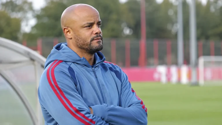 Vincent Kompany observeert een training naast een oefenveld.