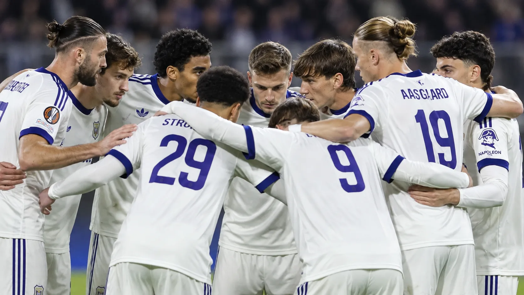 Anderlecht-spelers overleggen in een kring op het veld.