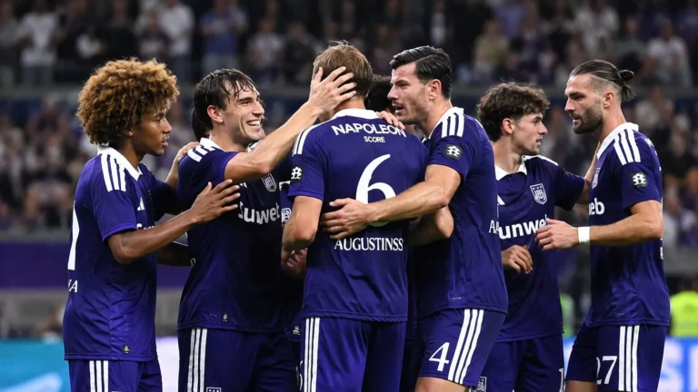 Een groep Anderlecht-spelers viert samen op het veld in paarse wedstrijdtenues.