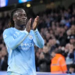 Jérémy Doku applaudisseert in zijn lichtblauwe Manchester City-tenue richting de tribunes.