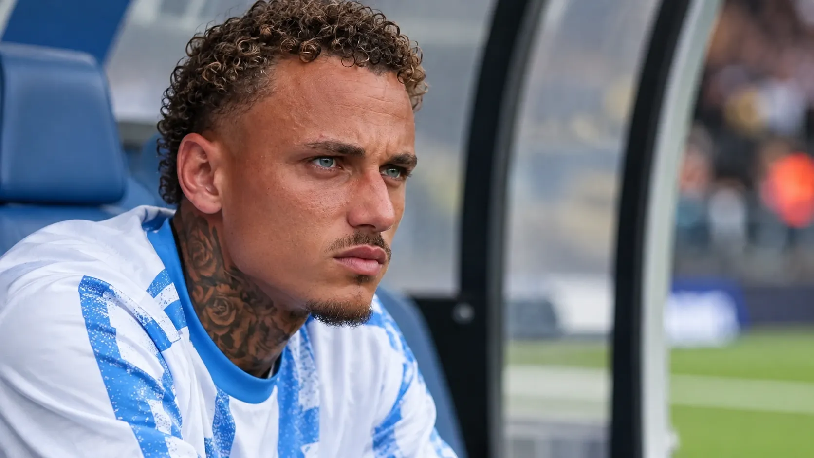 Noa Lang zit geconcentreerd op de bank langs het veld in zijn zichtbare bronkleding.
