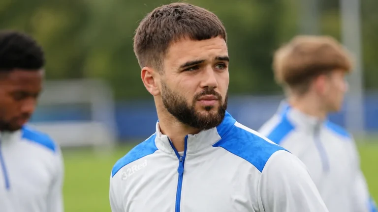 Nicolas Raskin in een wit-blauw trainingsvest op een grasveld.