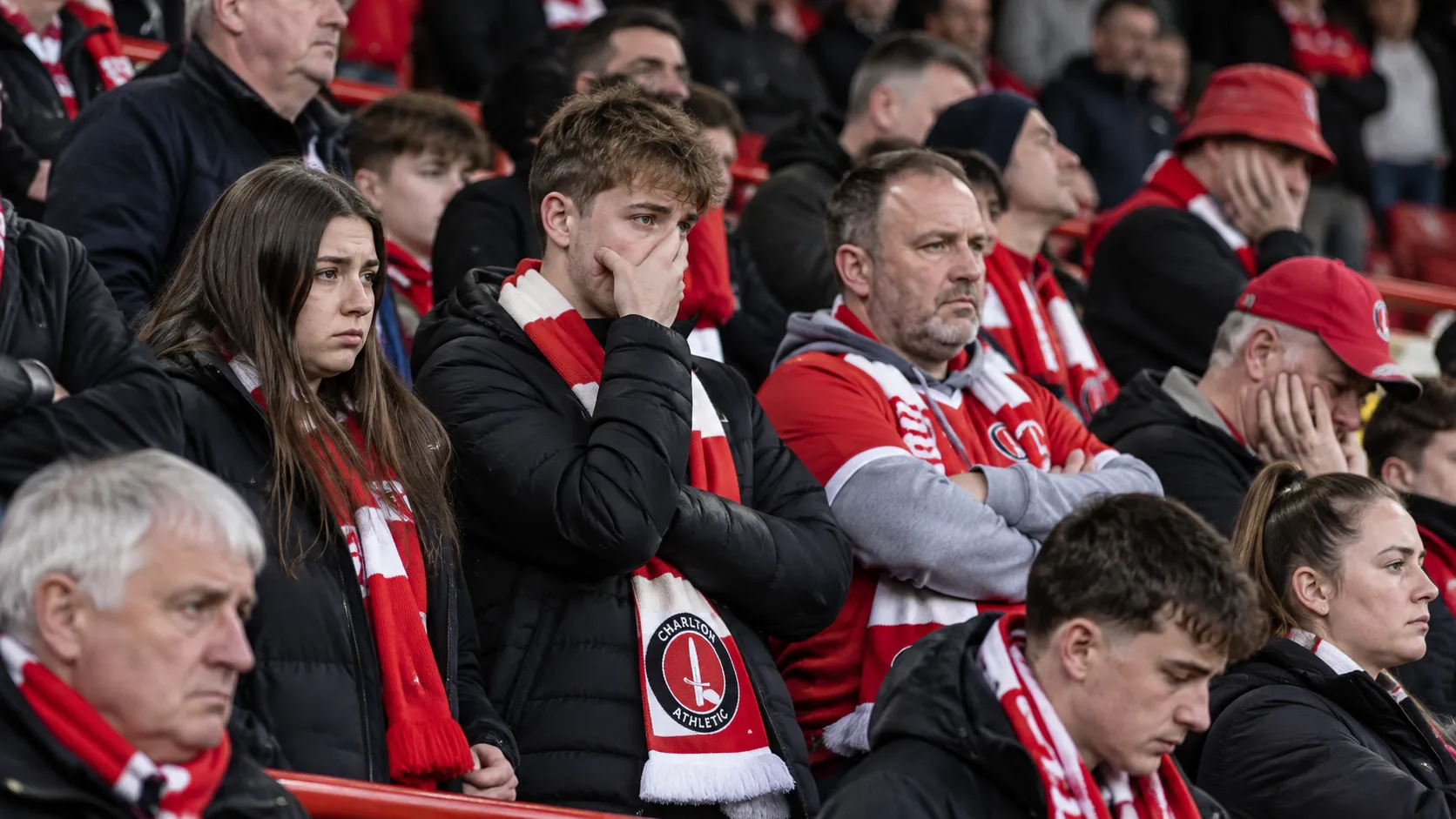 Teleurgestelde Charlton Athletic-supporters met rood-witte sjaals op de thuistribune.