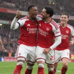 Arsenal-spelers vieren samen tijdens een wedstrijd in de regen.