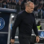 Massimiliano Allegri loopt gespannen langs de technische zone naast een Napoli-paneel op de dug-out.