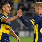 Twee STVV-spelers in blauw-geel tenue moedigen elkaar aan op het veld.