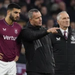 Een Burnley-speler naast twee leden van de staf aan de zijlijn.