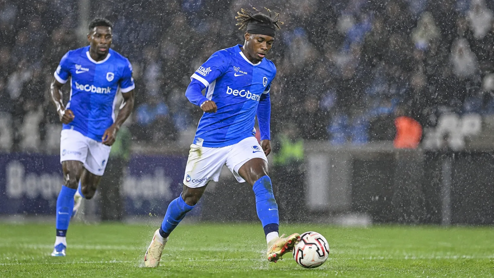 Noah Adedeji-Sternberg van KRC Genk controleert de bal tijdens een regenachtige wedstrijd.