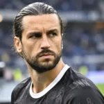 Christian Burgess van KAA Gent kijkt geconcentreerd langs de rand van het veld.