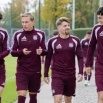 Een groep Anderlechtspelers in bordeaux trainingskleding op een trainingsveld.