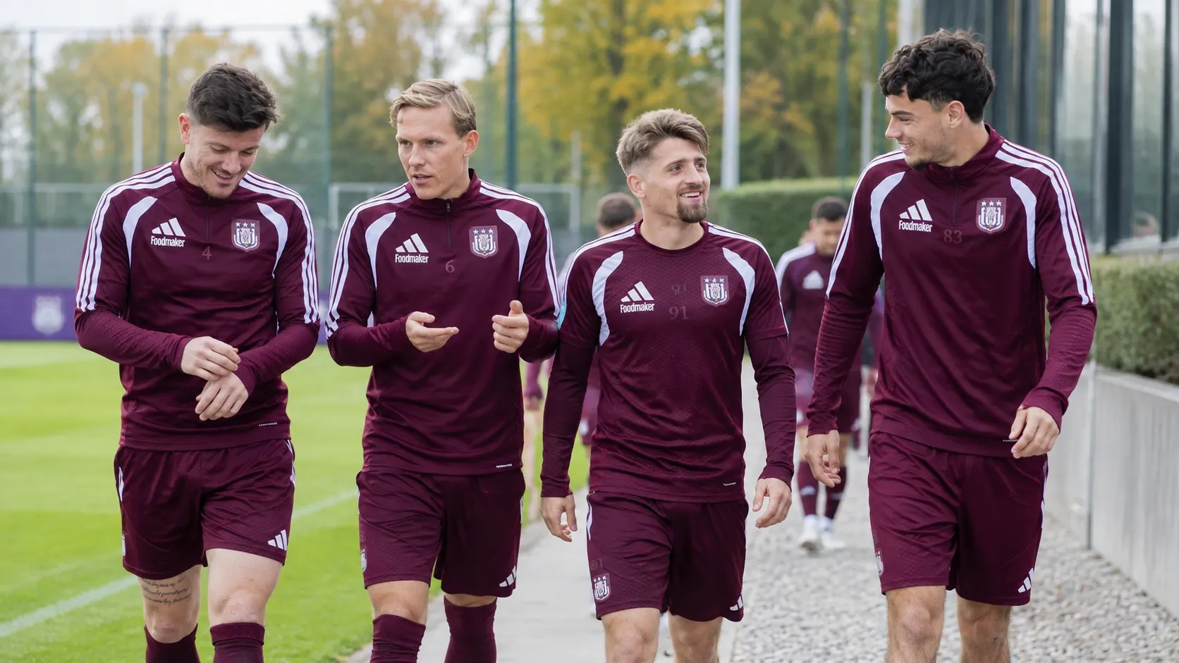 Een groep Anderlechtspelers in bordeaux trainingskleding op een trainingsveld.