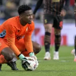 Matthieu Epolo van Standard hurkt op het veld met de bal in zijn handschoenen.