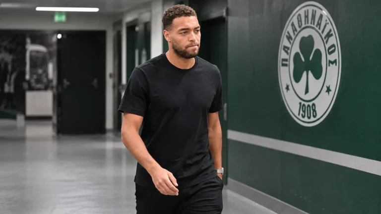 Cyriel Dessers loopt na een Europese wedstrijd door een stadiongang met een Panathinaikos-embleem op de wand.