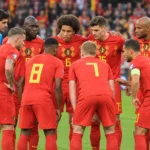 Een groep Belgische nationale spelers in rode tenues poseert voor een interland op het veld.