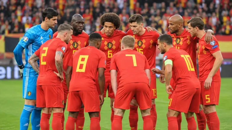 Een groep Belgische nationale spelers in rode tenues poseert voor een interland op het veld.