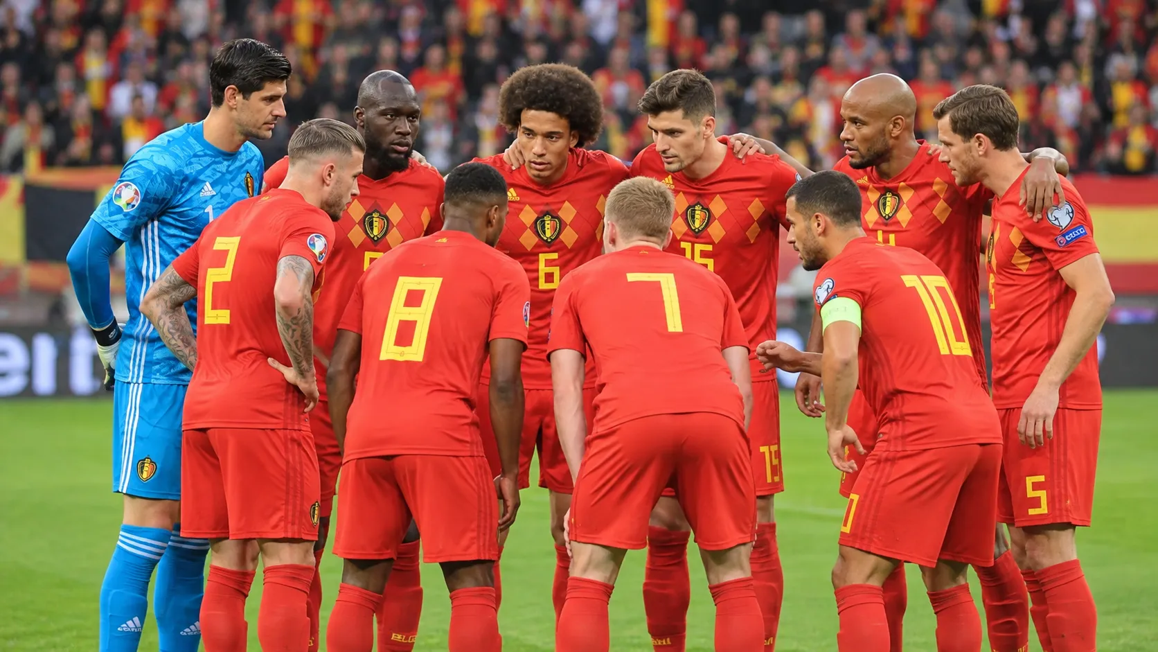 Een groep Belgische nationale spelers in rode tenues poseert voor een interland op het veld.