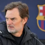 Ronald de Boer tijdens een interview met een subtiel Barcelona-embleem in de mediaomgeving.