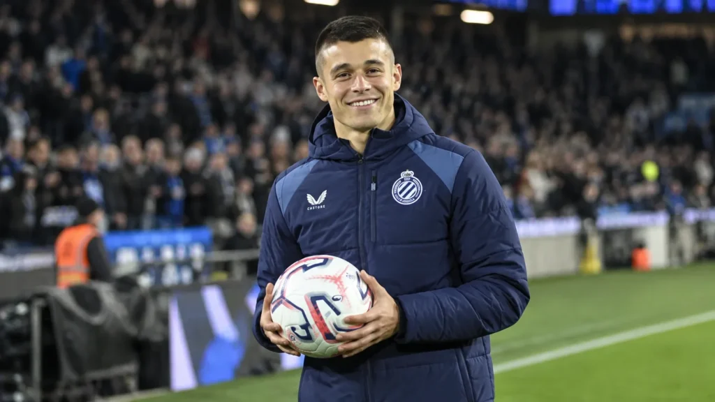Nicolo Tresoldi van Club Brugge met een wedstrijdbal en een individuele trofee langs het veld.