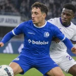 Een speler van KAA Gent in blauw strijdt om de bal tijdens een wedstrijdmoment.