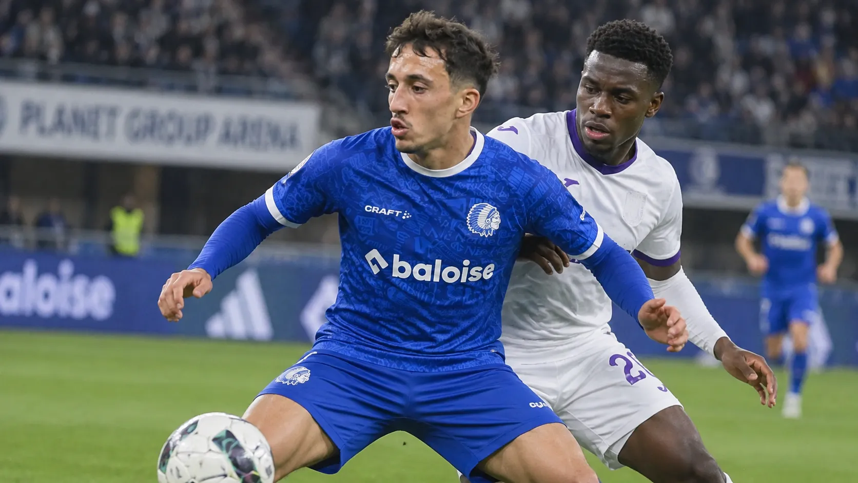 Een speler van KAA Gent in blauw strijdt om de bal tijdens een wedstrijdmoment.