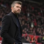 Michael Carrick staat langs de zijlijn in een voetbalstadion.