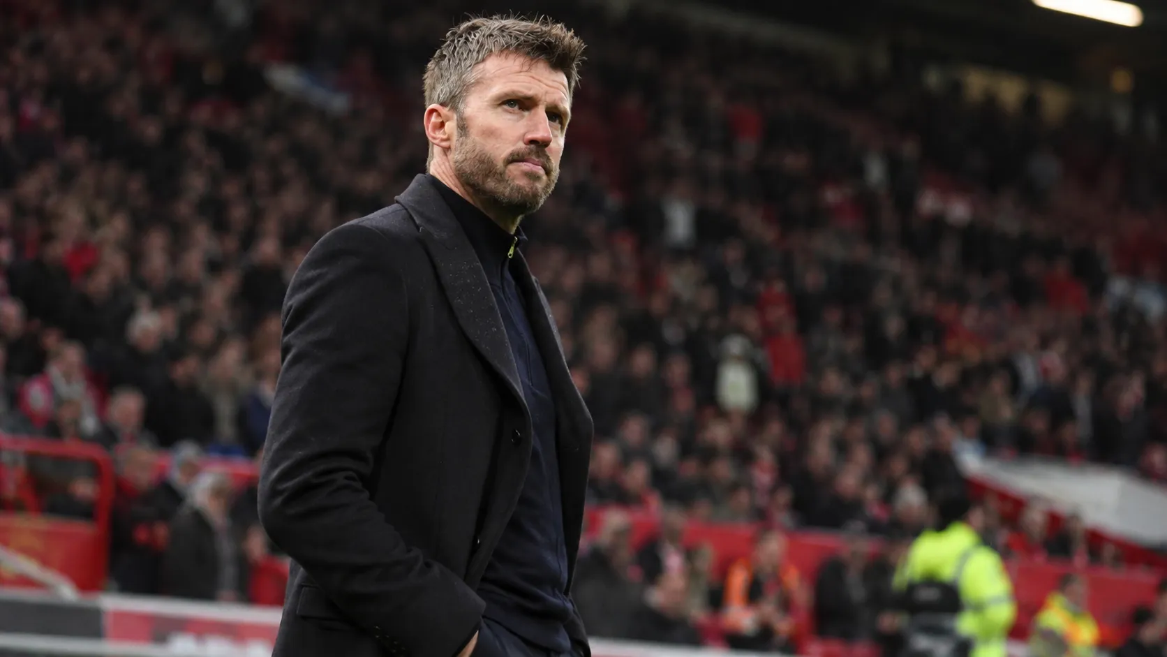 Michael Carrick staat langs de zijlijn in een voetbalstadion.