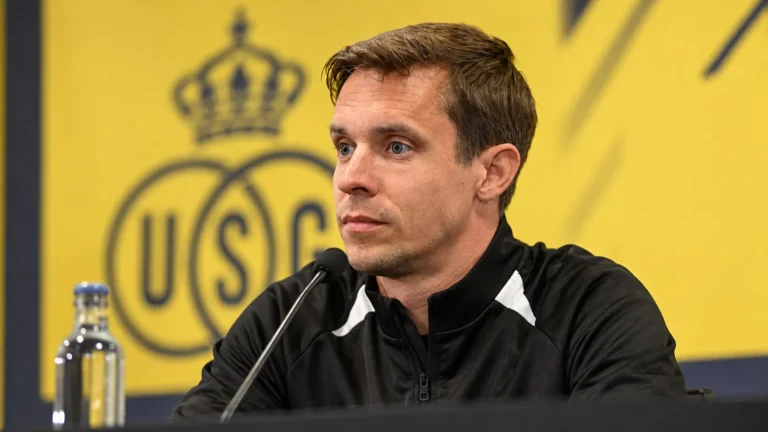 Een Union-coach in een zwarte trainingsjas tijdens een persmoment.