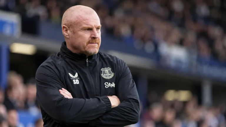 Sean Dyche in een donkere Everton-trainingsjas langs de zijlijn.