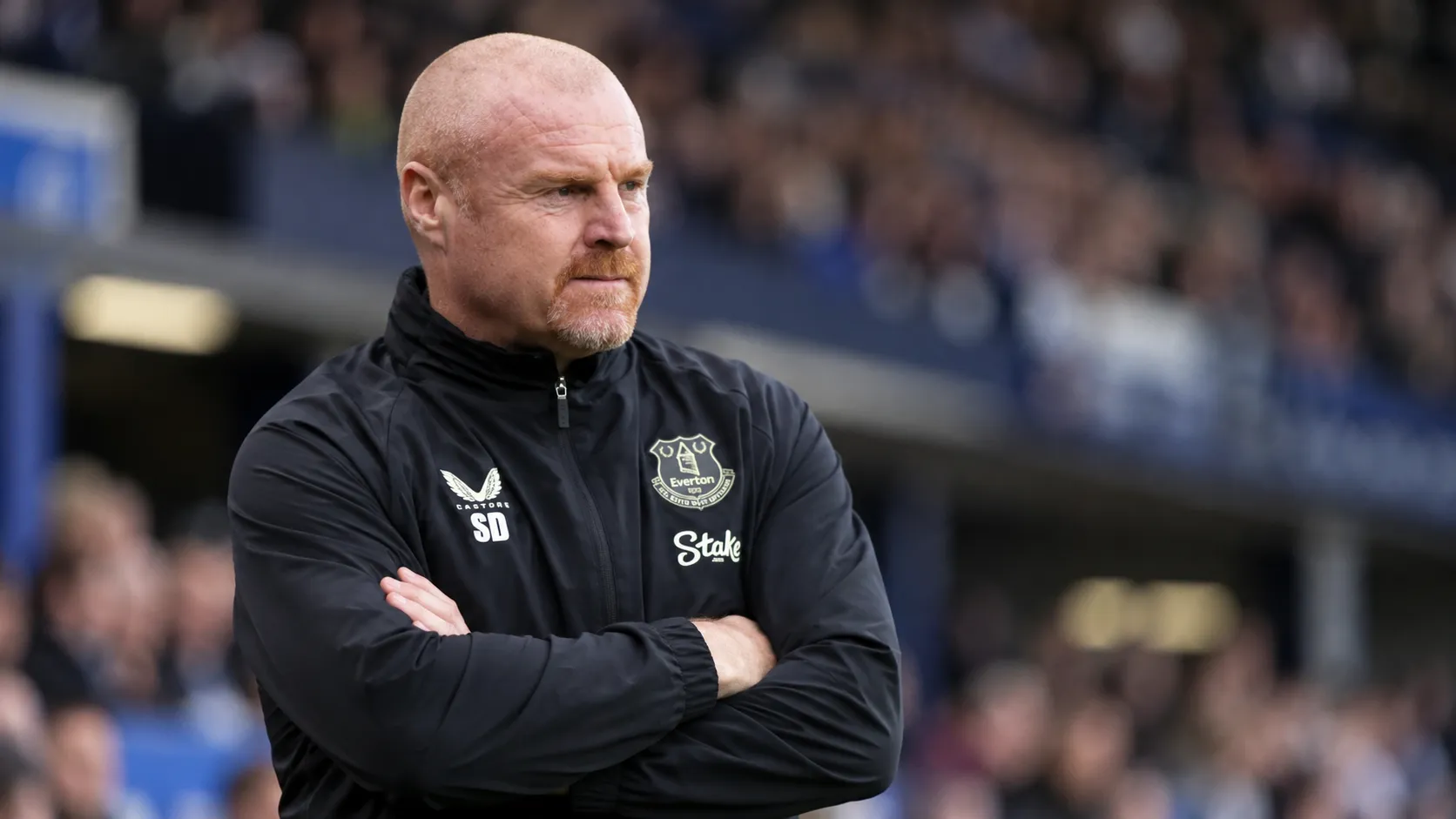 Sean Dyche in een donkere Everton-trainingsjas langs de zijlijn.