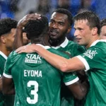 Een groep Lommel-spelers viert samen in de regen op het veld.